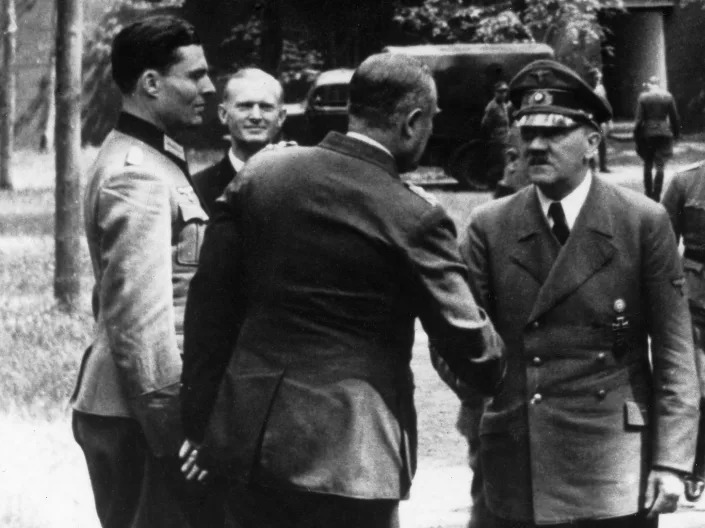 Col. Claus von Stauffenberg looks on as Adolf Hitler welcomes Gen. Karl Bodenschatz on July 7, 1944.