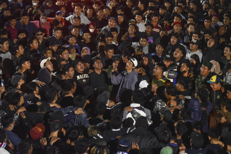 Soccer fans chant slogans during vigil for the victims of Saturday's soccer riots, in Malang, East Java, Indonesia, Sunday, Oct. 2, 2022. Police firing tear gas after an Indonesian soccer match in an attempt to stop violence triggered a disastrous crush of fans making a panicked, chaotic run for the exits, leaving a large number of people dead, most of them trampled upon or suffocated. (AP Photo/Dicky Bisinglasi)