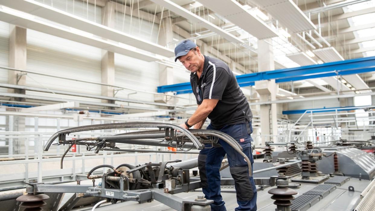 Klaus David, Elektriker in Rente bei der Deutschen Bahn, prüft auf einer Lokomotive im Nürnberger Bahnwerk den Stromabnehmer. Foto: Daniel Karman