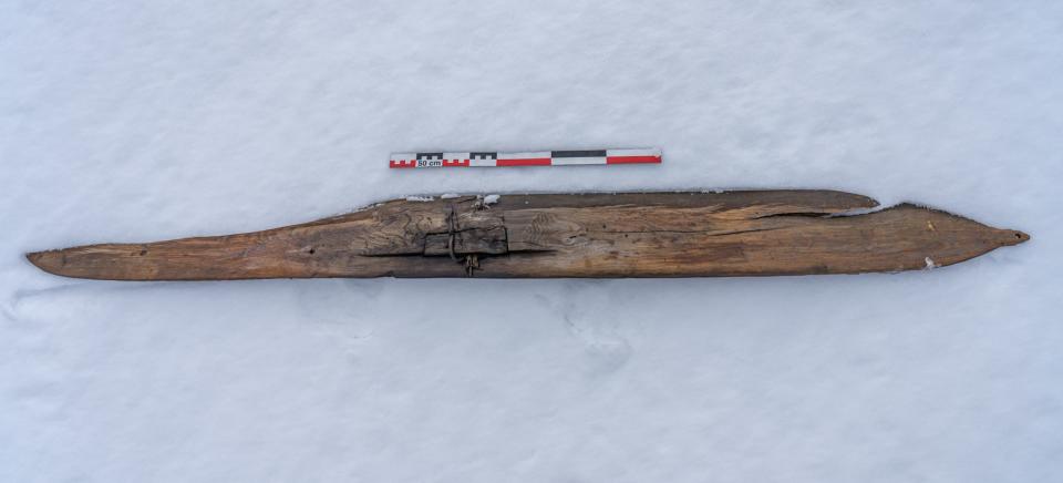 A 1,300-year-old wooden ski shown alongside a ruler atop a snowy mountain in Norway.
