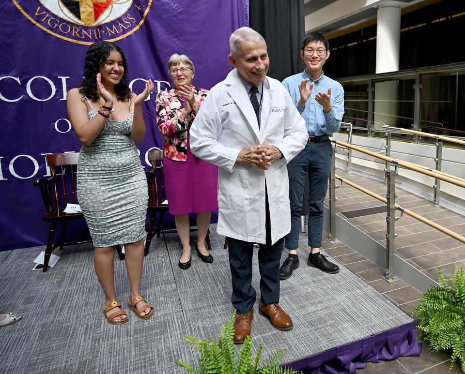 Dr. Anthony Fauci puts on a doctor's smock during a rededication ceremony at the College of the Holy Cross in June, when the Worcester college named its science complex in his honor.