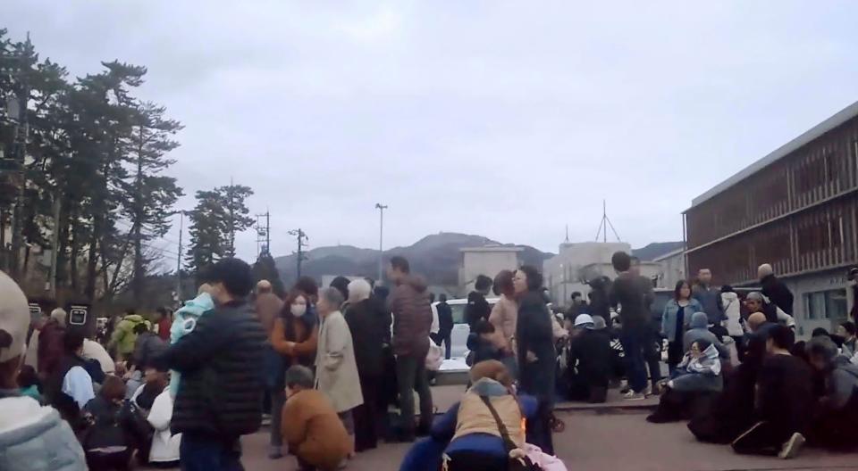 In this image from a video, people take shelter at a parking lot of a junior high school after an earthquake in Wajima, Ishikawa prefecture, Japan Monday, Jan. 1, 2024. Japan issued tsunami alerts Monday after a series of strong quakes in the Sea of Japan. (Kyodo News via AP)