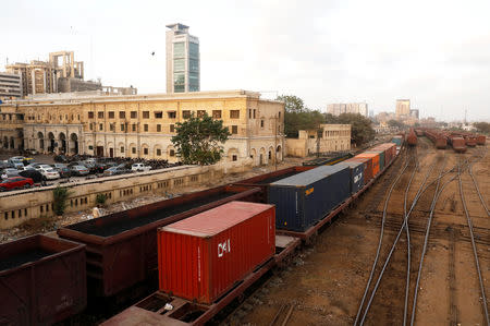Cargo trains carrying shipping containers and coal dust, crossing under a bridge with the backdrop of City Station, built in the British Raj era, in Karachi, Pakistan September 24, 2018. REUTERS/Akhtar Soomro