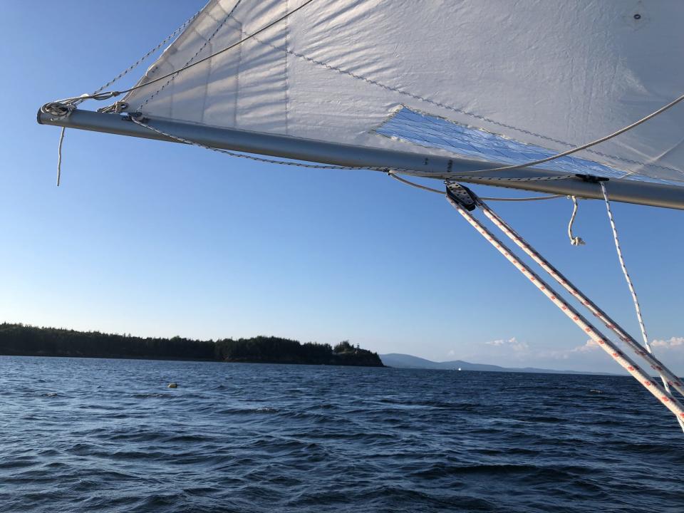 A view from the sailboat of a white sail and blue water