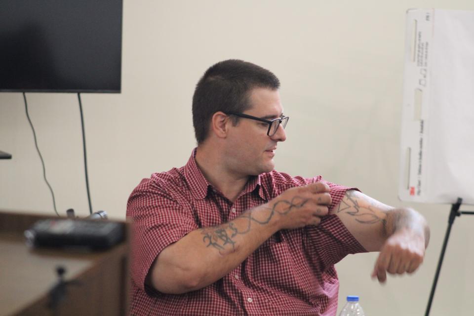 Defendant Eric Molitor explains his tattoos in court, showing that none of them have any militia significance.