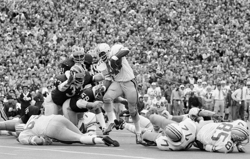 FILE - In this Nov. 24, 1973, file photo, Ohio State's Archie Griffin picks up some of his game-high 163 yards against Michigan during an NCAA college football game in Ann Arbor, Mich., as Michigan's Walt Williamson (91), Carl Russ (33) and Steve Strinko (59) defend. No. 2 Ohio State and No. 3 Michigan have a chance to add to the lore of The Game, a football rivalry that is widely regarded as one of the best in sports, when they meet again, on Saturday, Nov. 26, 2016. (AP Photo/File)