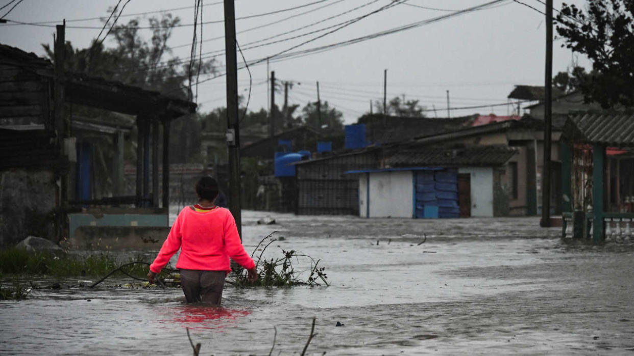 A woman walks through a flooded street in Batabano, Cuba, on September 27, 2022, during the passage of hurricane Ian. - Hurricane Ian made landfall in western Cuba early Tuesday, with the storm prompting mass evacuations and fears it will bring widespread destruction as it heads for the US state of Florida. (Photo by YAMIL LAGE / AFP)