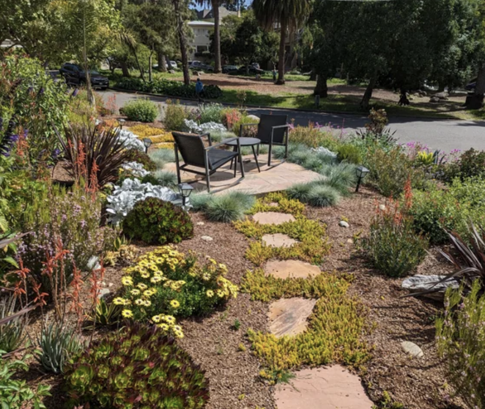 Someone's yard that's set up with a table and chairs, surrounded by plants and flowers