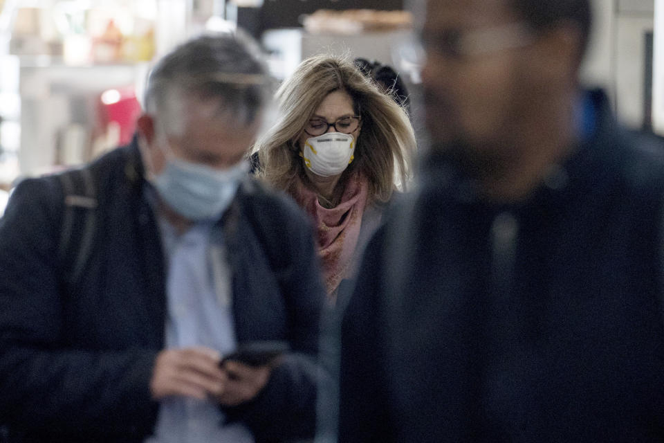 People wearing masks walk through a terminal at Ronald Reagan Washington National Airport, Monday, March 16, 2020, in Arlington, Va. (AP Photo/Andrew Harnik)