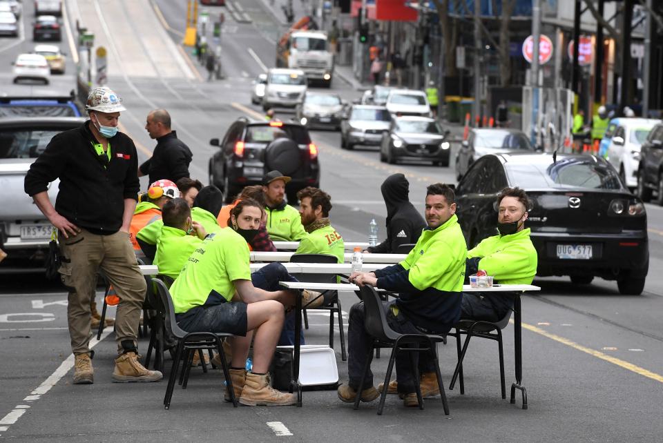 Construction workers take their lunch break on a busy street, disrupting traffic in Melbourne on September 17 to protest the closing of their onsite tea rooms by health officials. Source: Getty