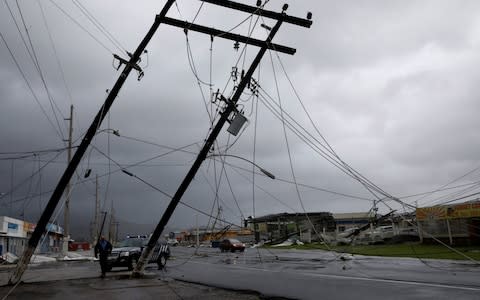 A police officer walks next to damaged electrical installations after the area was hit by Hurricane Maria in Guayama - Credit: REUTERS/Carlos Garcia Rawlins