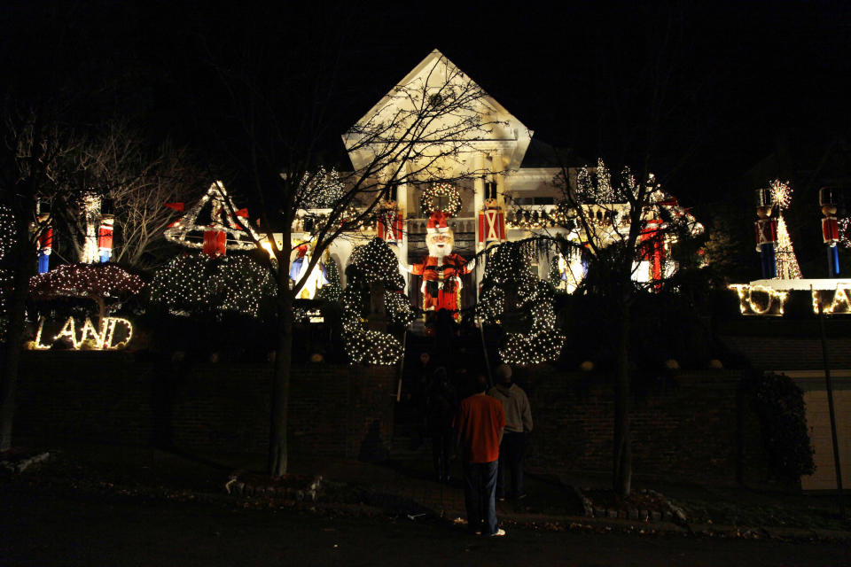 This Dec. 4, 2012 photo shows spectators viewing an elaborately decorated home for the holidays in the Brooklyn borough of New York. Each holiday season, tour operator Tony Muia takes tourists from around the world on his “Christmas Lights & Cannoli Tour” visiting the Brooklyn neighborhoods of Dyker Heights and Bay Ridge, where locals take pride in over-the-top holiday light displays. (AP Photo/Seth Wenig)