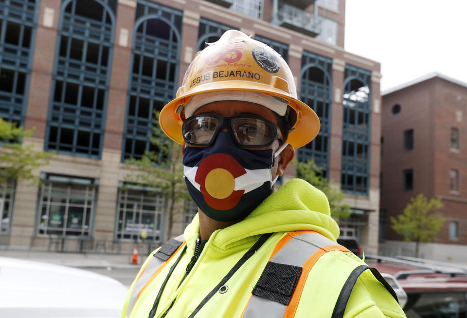 Construction worker Jesus Bejarano wears a face mask bearing the design of the flag of Colorado as he heads back to a nearby site while other workers report to their jobs for the first time in nearly two months with the expiration of the city's stay-at-home order to check the spread of the new coronavirus Saturday, May 9, 2020, in Denver. (AP Photo/David Zalubowski)