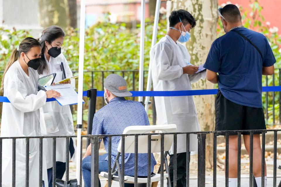 Healthcare workers with New York City Department of Health and Mental Hygiene help people register for the monkeypox vaccine at one of the City's vaccination sites on Tuesday, July 26, 2022, in New York. New York declared a state disaster emergency due to monkeypox on July 29. (AP Photo/Mary Altaffer)