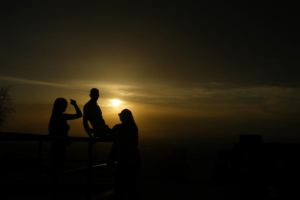 A group of friends watch the sunset atop South Mountain, Sunday, July 30, 2023, in Phoenix. Phoenix sizzled through its 31st consecutive day of at least 110 degrees Fahrenheit (43.3 Celsius) and other parts of the country grappled Sunday with record temperatures after a week that saw significant portions of the U.S. population subject to extreme heat. (AP Photo/Matt York)