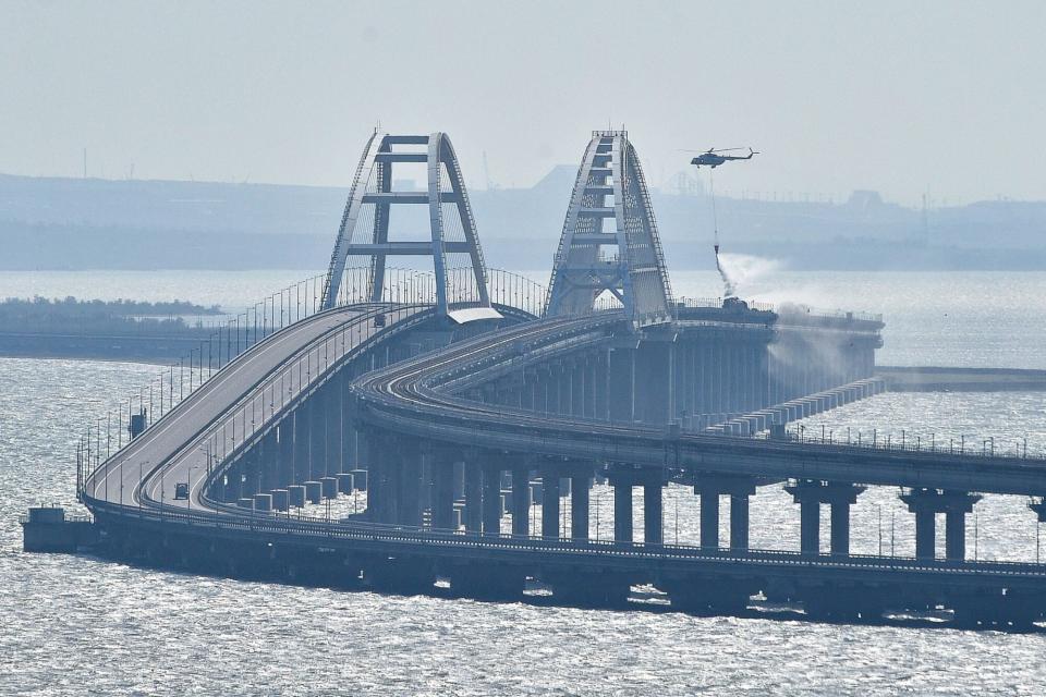 Mandatory Credit: Photo by Uncredited/AP/Shutterstock (13448163a) Helicopter drops water to stop fire on Crimean Bridge connecting Russian mainland and Crimean peninsula over the Kerch Strait, in Kerch, . Russian authorities say a truck bomb has caused a fire and the collapse of a section of a bridge linking Russia-annexed Crimea with Russia. The bridge is a key supply artery for Moscow's faltering war effort in southern Ukraine Russia Ukraine, Kerch - 08 Oct 2022