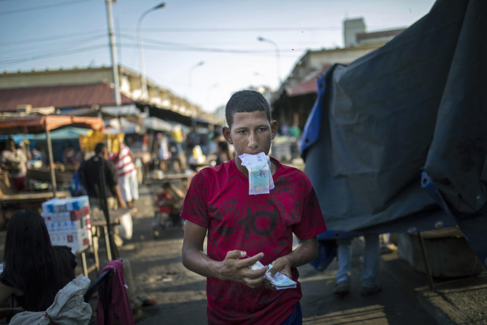 A flea market vendor counts his Bolivar bills in Maracaibo, Venezuela, May 16, 2019. Maracaibo is Venezuela's second-largest city and a hub of the once-booming oil industry. (AP Photo/Rodrigo Abd)