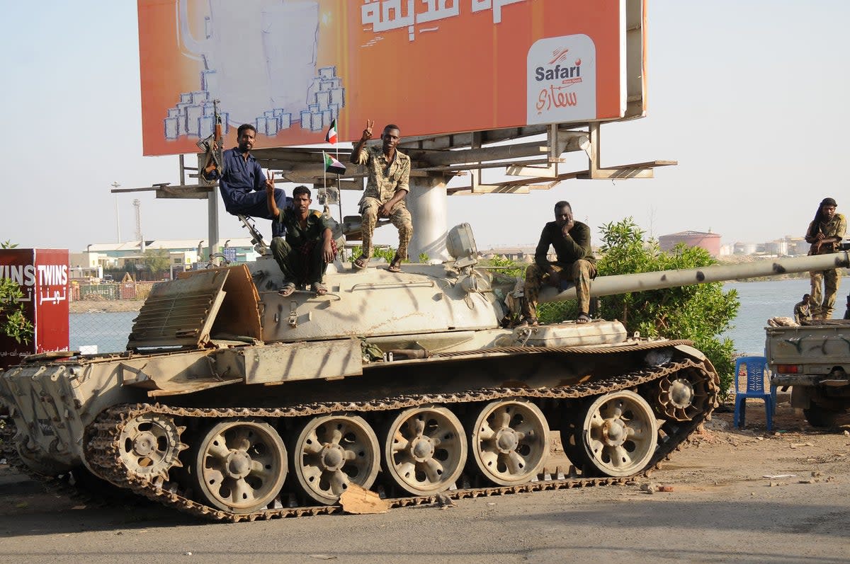 Sudanese army soldiers, loyal to army chief Abdel Fattah al-Burhan, sit atop a tank in the Red Sea city of Port Sudan, on 20 April 2023 (AFP via Getty Images)