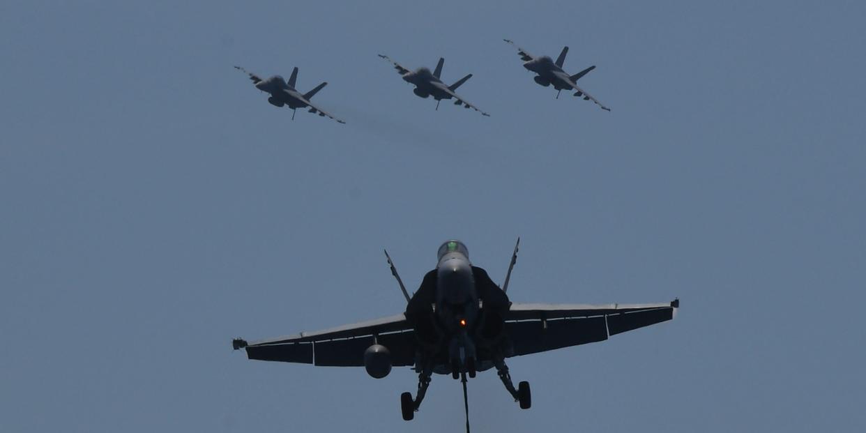 A US FA-18 hornet fighter (F) prepares to land while other fighter jets fly behind during a routine training aboard US aircraft carrier Theodore Roosevelt in the South China sea on April 10, 2018.