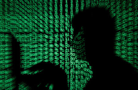 FILE PHOTO: A man holds a laptop computer as cyber code is projected on him in this illustration picture taken on May 13, 2017. REUTERS/Kacper Pempel/File Photo