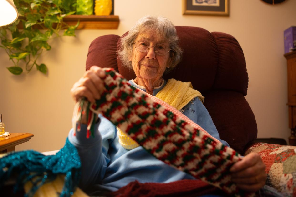 Jacqualin Geasland, 94, holds a crocheted scarf. Geasland's family estimated she has produced more than 500 scarfs, hats and blankets this year that have been donated to the community.