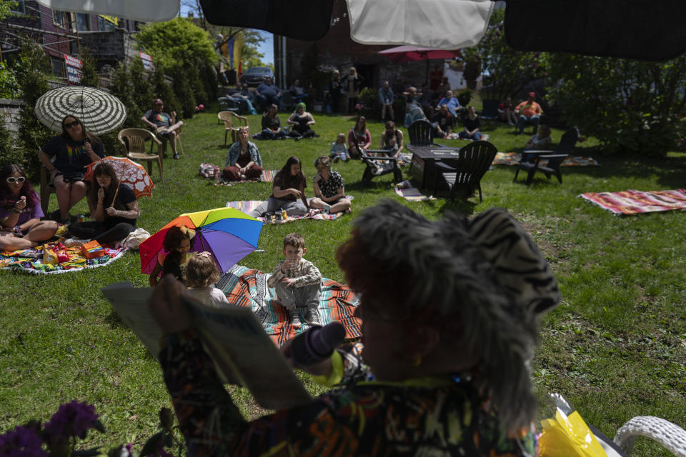 Drag queen Alexus Daniels reads "Coat of Many Colors" by Dolly Parton to children, their families, and friends at "Drag Storytime!" in Mt. Carmel, Pa., in the garden at the Pink Moon Collective, Saturday, May 6, 2023. (AP Photo/Carolyn Kaster)