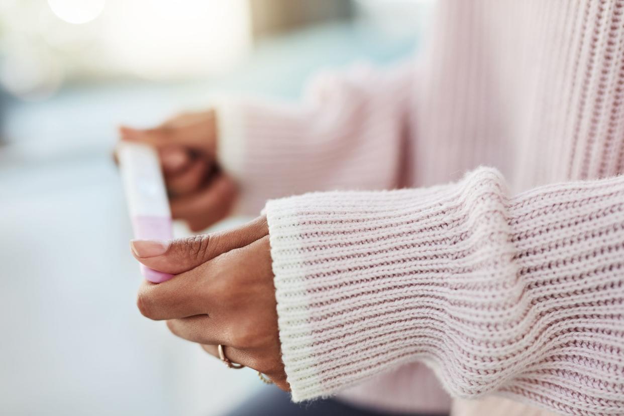 Cropped shot of an unrecognizable woman sitting on her bed alone and waiting for a pregnancy test result at home