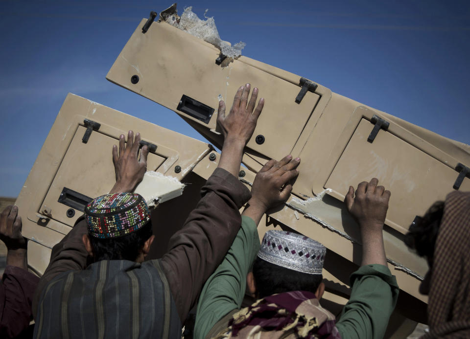 FILE- In this file photo taken Nov. 2, 2013, Afghans load pieces of a a destroyed U.S military armored car into their vehicle at a junk yard in Kandahar, southern Afghanistan. As the United States military packs up to leave Afghanistan, ending 13 years of war, it is looking to sell or dispose of billions of dollars in military hardware, including its sophisticated and highly specialized mine resistant vehicles, but finding a buyer is complicated in a region where relations between neighboring countries are mired in suspicion and outright hostility. (AP Photo/Anja Niedringhaus, file)