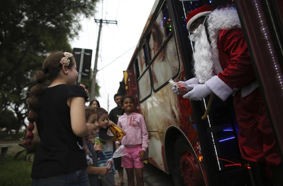 Bus driver Edilson, also known as "Fumassa", greets children as he wears a Santa Claus outfit inside an urban bus decorated with Christmas motives in Santo Andre