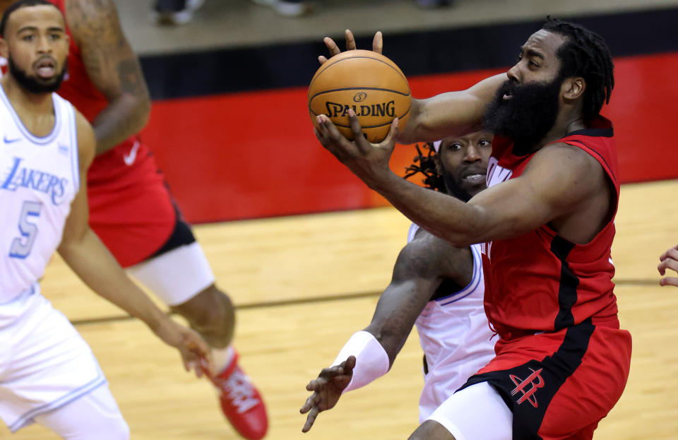 James Harden sostiene el balón con las dos manos y ataca la canasta mientras jugadores de los Lakers intentan defenderle.