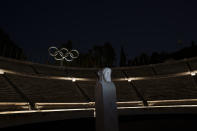 The Olympic rings are seen behind the double face marble statue known as Hermes in the marble Panathinean Stadium, venue of the first modern Olympics in 1896, in Athens, early Friday, April 5, 2024. (AP Photo/Petros Giannakouris)