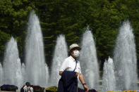 A man wearing a protective mask to help curb the spread of the coronavirus walks through a park Wednesday, April 21, 2021, in Tokyo. The Japanese capital confirmed more than 840 new coronavirus cases on Wednesday. (AP Photo/Eugene Hoshiko)