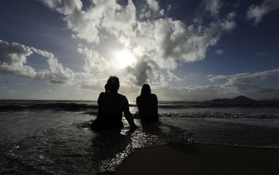 Spectators watch the solar eclipse while sitting in the surf in Palm Cove, Australia.