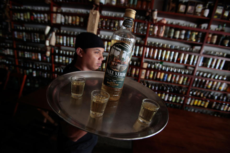 In this April 11, 2013 photo, waiter Ivanildo Soares serves a bottle of cachaca, Brazil's national spirit, at the "Adega da Cachaca" cellar in Brasilia, Brazil. The vast majority of cachaca is consumed domestically, much of it sipped in Brazil's famed caipirinha cocktails with lime, sugar and crushed ice.(AP Photo/Eraldo Peres)