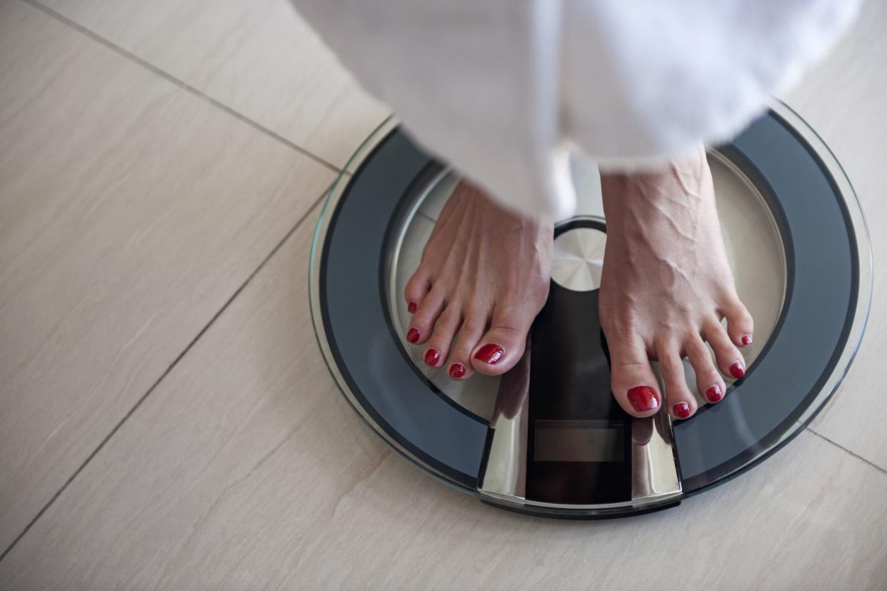 Woman standing in bath robe on scale barefoot