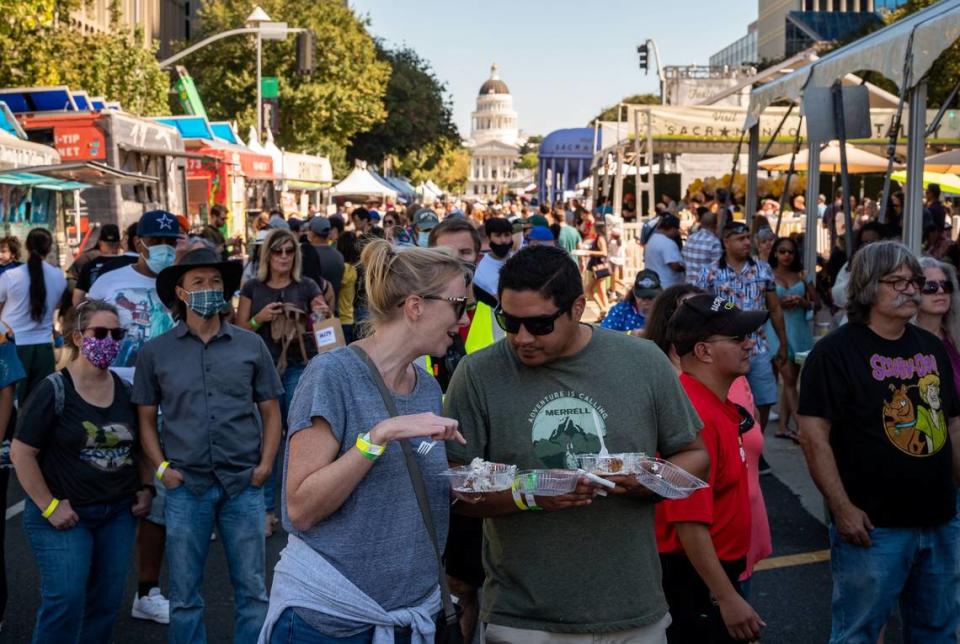 Emily Gardner, left, and Orlando Olivas, Sacramento residents who are engaged to be married, eat beignets and listen to live music at the Farm-to-Fork Festival on Saturday, Sept. 18, 2021, in downtown Sacramento.