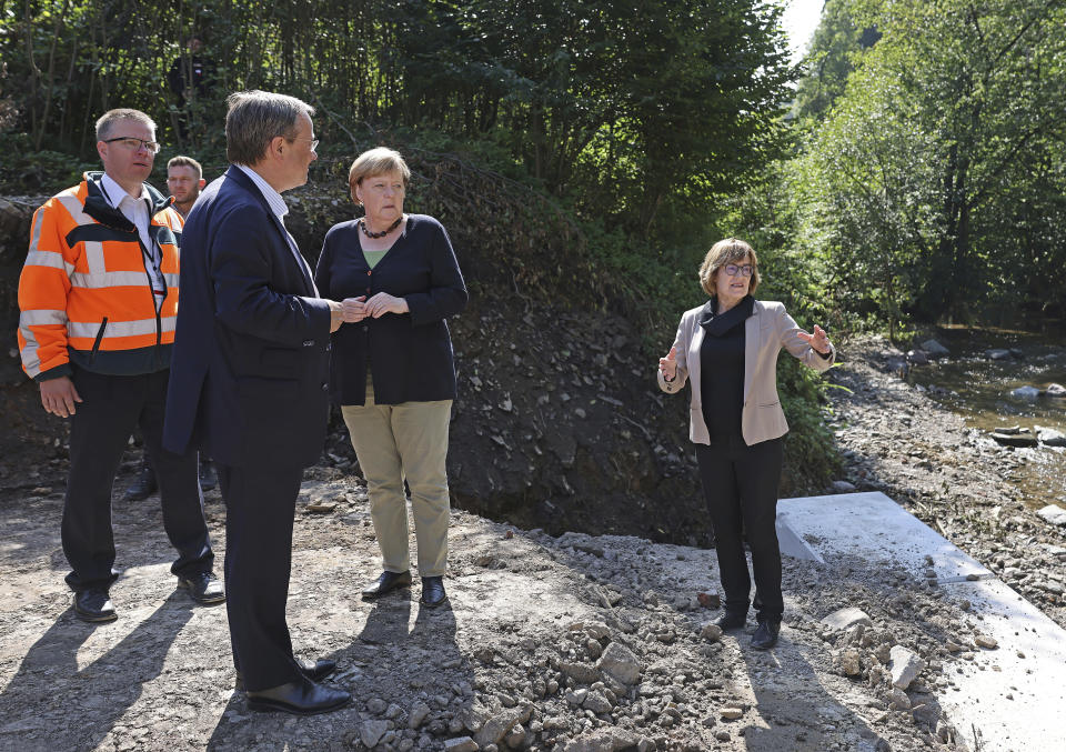 German Chancellor Angela Merkel, centre, and Armin Laschet, foreground left, candidate for chancellor of the CDU/CSU and chairman of the CDU, listen to Petra Beckefeld, right, from the road construction company Strassen, as they visit areas affected by flooding, in Hagen, Germany, Sunday, Sept. 5, 2021. (Oliver Berg/Pool Photo via AP