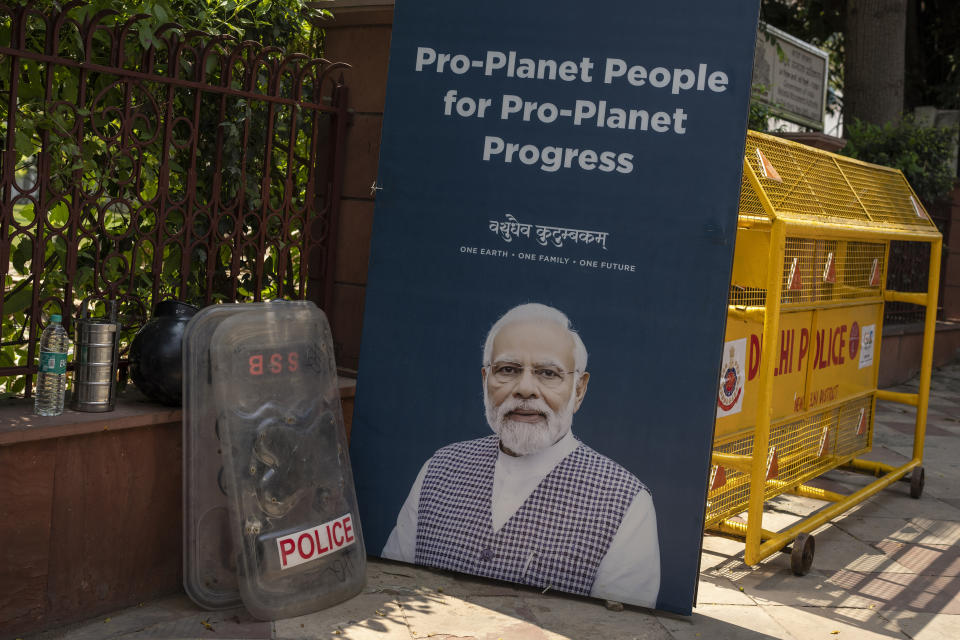 Police shields rest against a fence next to the poster of Indian Prime Minister Narendra Modi on a road leading to the venue for this week's summit of the Group of 20 nations in New Delhi, India, Thursday, Sept. 7, 2023. (AP Photo/Altaf Qadri)