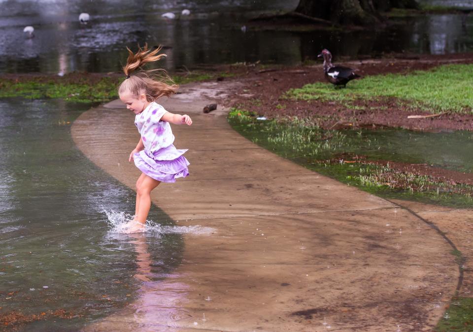 Skylar Larrosa, 4, leaps off of a flooded sidewalk at Tuscawilla Park in Ocala on Tuesday.