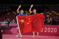 Ma Long of China, right and Fan Zhendong of China pose with a Chinese national flag after their gold medal match of the table tennis men's singles at the 2020 Summer Olympics, Friday, July 30, 2021, in Tokyo. (AP Photo/Kin Cheung)