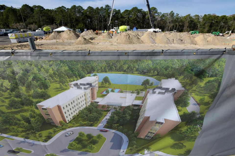 An artist's rendering shows the planned residence hall for the University of North Florida's Hicks Honors College, with construction ongoing in the background.