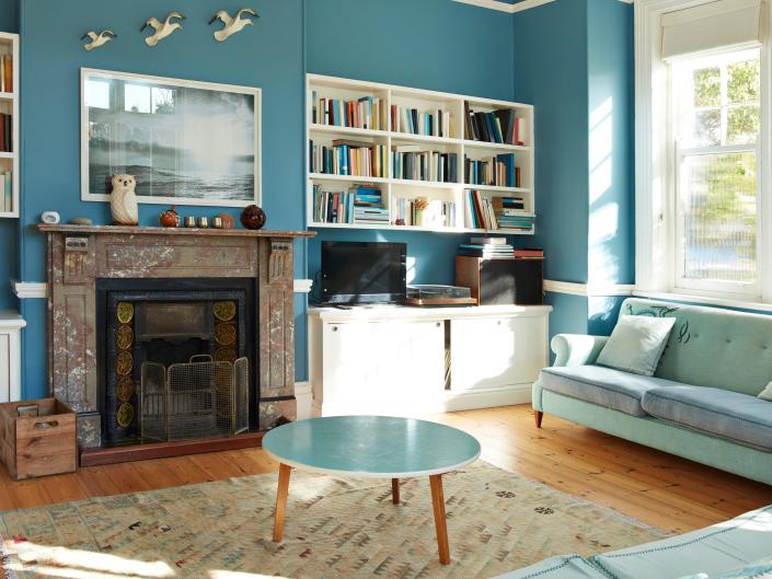 blue living room round table blue couch fireplace bookshelves window rug