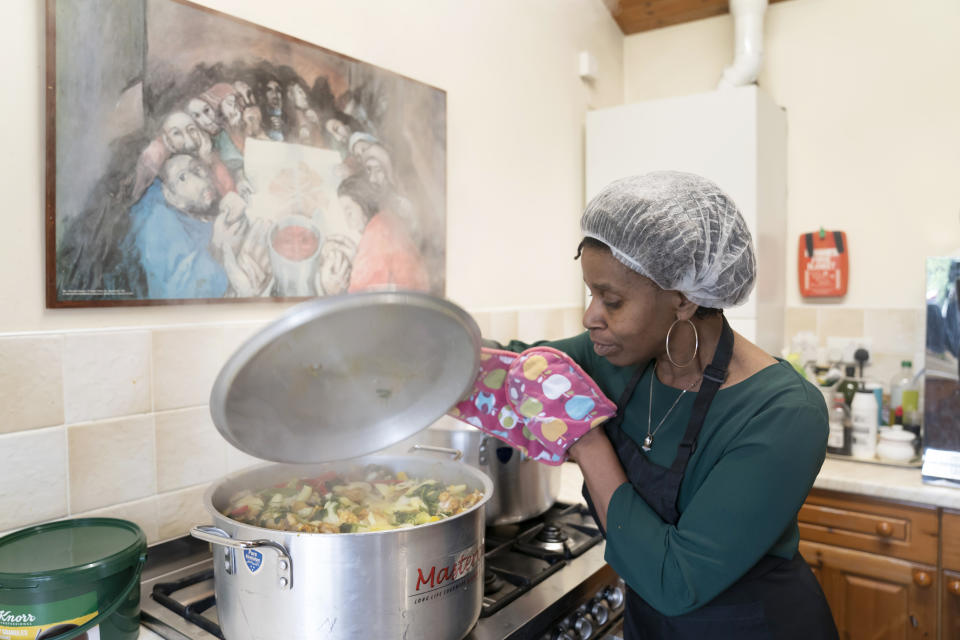 Chief coordinator Glenda Andrew checks the pot as she prepares West Indian meals with members of the Preston Windrush Covid Response team, at the Xaverian Sanctuary, in Preston, England, Friday Feb. 19, 2021. Once a week they distribute meals to people in Preston and surrounding communities in northwestern England that have recorded some of the U.K.’s highest coronavirus infection rates. The meal program grew out of Andrew’s work with Preston Windrush Generation & Descendants, a group organized to fight for the rights of early immigrants from the Caribbean and other former British colonies who found themselves threatened with deportation in recent years. (AP Photo/Jon Super)