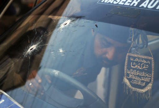 A Pakistani police officer examines a bullet-riddled police vehicle following an attack by gunmen in Karachi on Thursday. A suicide bomber targeted a police official in Pakistan's financial capital , killing at least three people and wounding 13 others, police said