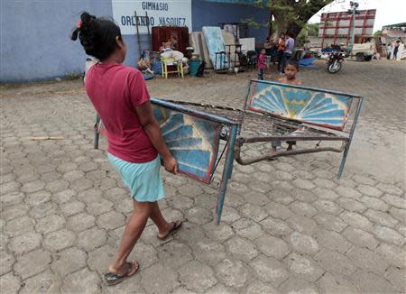 A woman and a boy carry a bed frame at a shelter for people affected by the earthquake in Managua April 11, 2014. REUTERS/Oswaldo Rivas