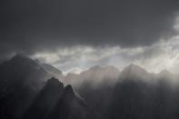 The sun's rays shine through clouds over the Karakorum mountain range next to the China-Pakistan Friendship Highway near Tashkurgan in western Xinjiang province