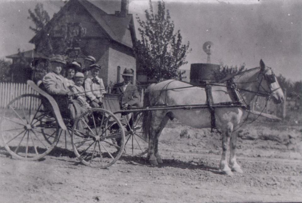 Unidentified individuals sit and pose by a horse and buggy around 1907 with the Maxwell House, 2340 W. Mulberry St., visible in the background.