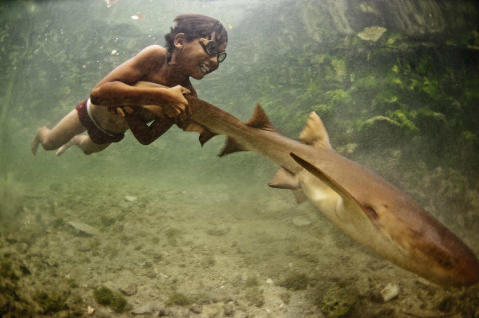 Enal, a young sea nomad, rides on the tail of a tawny nurse shark, in Sulawesi, Indonesia. Marine nomadism has almost completely disappeared in South East Asia as a result of severe marine degradation. I believe children such as Enal have stories that could prove pivotal in contemporary marine conservation. (Photograph by James Morgan, <a href="http://travel.nationalgeographic.com/travel/traveler-magazine/photo-contest/2012/" rel="nofollow noopener" target="_blank" data-ylk="slk:National Geographic Traveler Photo Contest;elm:context_link;itc:0;sec:content-canvas" class="link ">National Geographic Traveler Photo Contest</a>) <br> <br> <a href="http://travel.nationalgeographic.com/travel/traveler-magazine/photo-contest/2012/entries/recent-entries/" rel="nofollow noopener" target="_blank" data-ylk="slk:Click here;elm:context_link;itc:0;sec:content-canvas" class="link ">Click here</a> to see all contest entries <br> <a href="http://travel.nationalgeographic.com/travel/traveler-magazine/photo-contest/2012/entries/wallpaper/outdoor-scenes-week-7/" rel="nofollow noopener" target="_blank" data-ylk="slk:Click here;elm:context_link;itc:0;sec:content-canvas" class="link ">Click here</a> for contest wallpapers