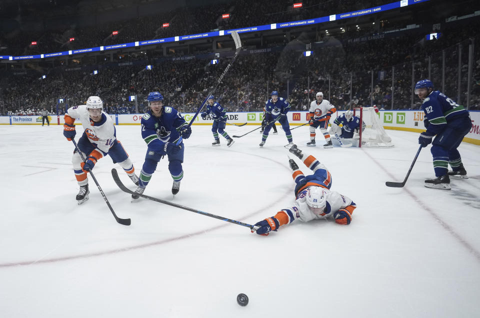 New York Islanders' Brock Nelson (29) dives for the puck Pierre Engvall, left, and Vancouver Canucks' Anthony Beauvillier, secon from left, and Ian Cole, right, watch during the third period of an NHL hockey game Wednesday, Nov. 15, 2023, in Vancouver, British Columbia. (Darryl Dyck/The Canadian Press via AP)