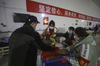 In this Friday, Feb. 21, 2020, photo, a volunteer distributes meals to patients at a temporary hospital at Tazihu Gymnasium in Wuhan in central China's Hubei province. China's leadership sounded a cautious note Friday about the country's progress in halting the spread of the new virus that has now killed more than 2,200 people, after several days of upbeat messages. (Chinatopix via AP)